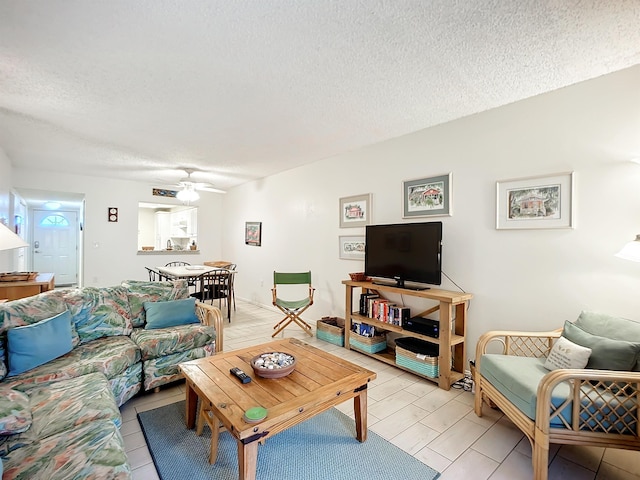 living room with ceiling fan and a textured ceiling