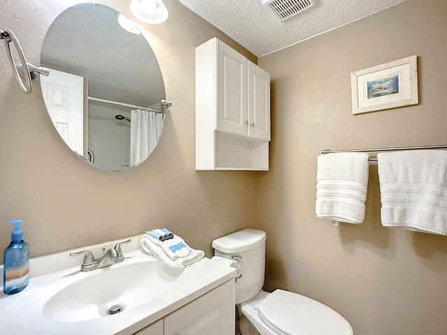 bathroom featuring curtained shower, vanity, a textured ceiling, and toilet