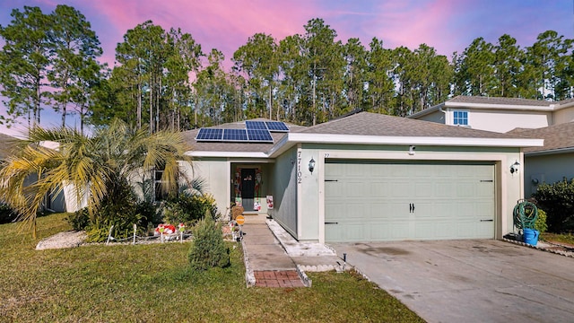 view of front of home with solar panels, a yard, and a garage