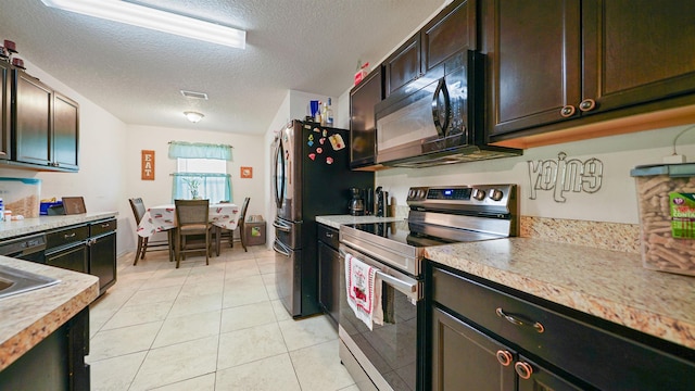 kitchen with dark brown cabinetry, light tile patterned flooring, black appliances, and a textured ceiling