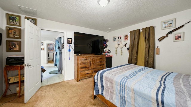 bedroom with light colored carpet and a textured ceiling