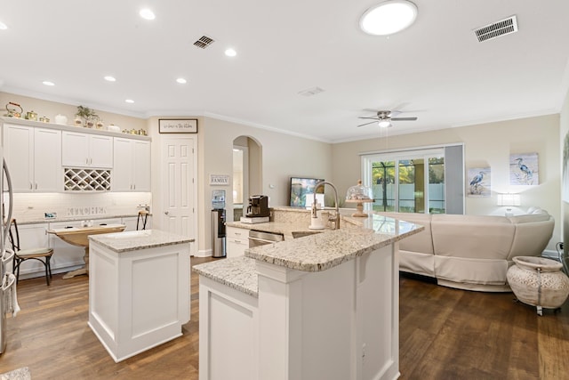 kitchen featuring light stone countertops, ceiling fan, dark hardwood / wood-style floors, an island with sink, and white cabinets