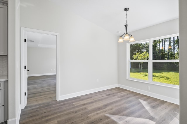 empty room with dark hardwood / wood-style flooring and a notable chandelier