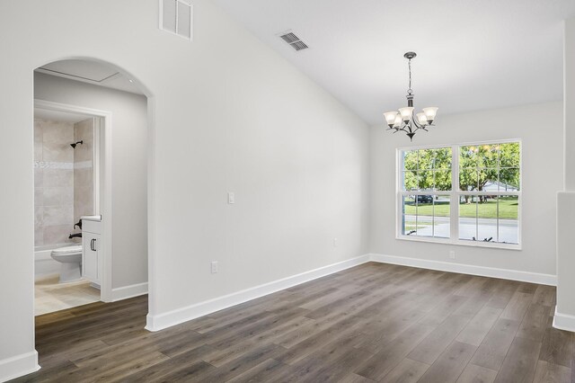 spare room with dark hardwood / wood-style floors and an inviting chandelier