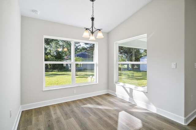 unfurnished dining area with a wealth of natural light, hardwood / wood-style floors, a chandelier, and lofted ceiling