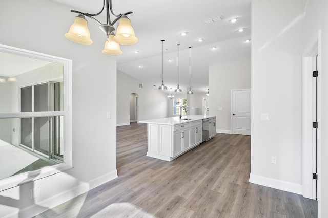 kitchen with a center island with sink, light hardwood / wood-style flooring, pendant lighting, and sink