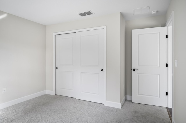 unfurnished bedroom featuring light colored carpet and a closet