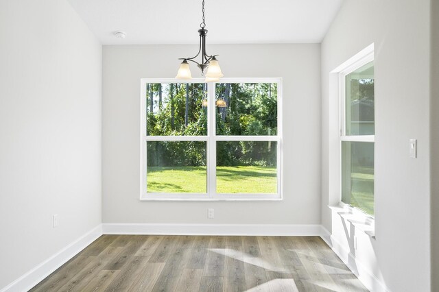 unfurnished dining area featuring hardwood / wood-style flooring, plenty of natural light, and a chandelier