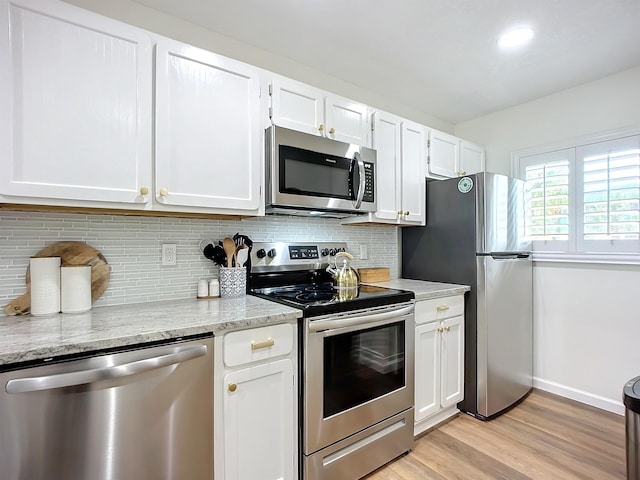 kitchen featuring light stone countertops, stainless steel appliances, tasteful backsplash, light hardwood / wood-style flooring, and white cabinets