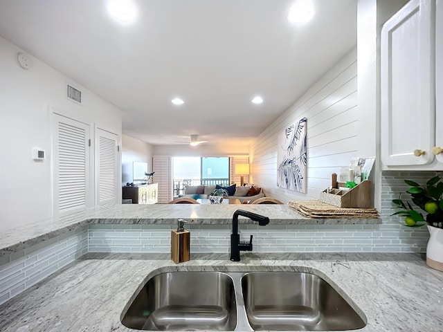 kitchen featuring white cabinets, light stone counters, and sink