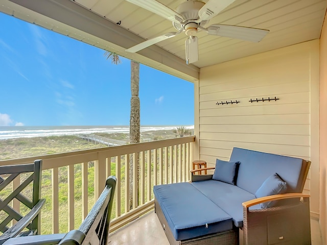 balcony featuring ceiling fan, a water view, and a beach view