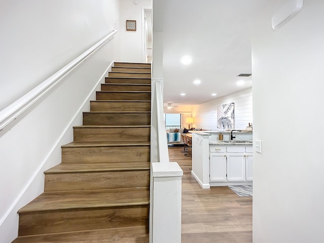 stairs with hardwood / wood-style flooring and sink