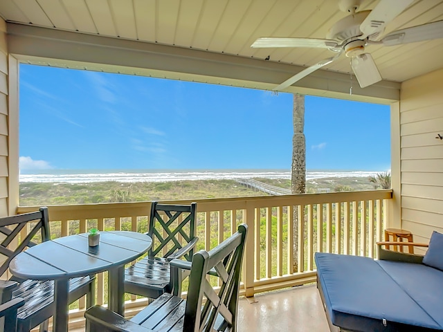 wooden terrace with ceiling fan, a water view, and a beach view