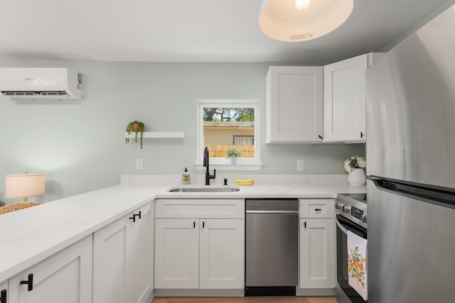 kitchen featuring appliances with stainless steel finishes, a sink, a wall mounted AC, white cabinets, and light countertops