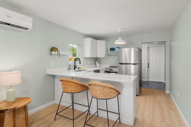 kitchen featuring stainless steel appliances, a wall mounted AC, light wood-style flooring, and a peninsula