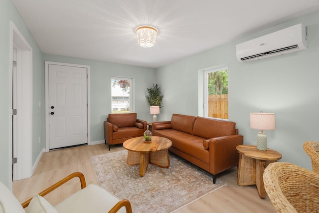 living room with a wall mounted air conditioner, light wood-style flooring, healthy amount of natural light, and baseboards