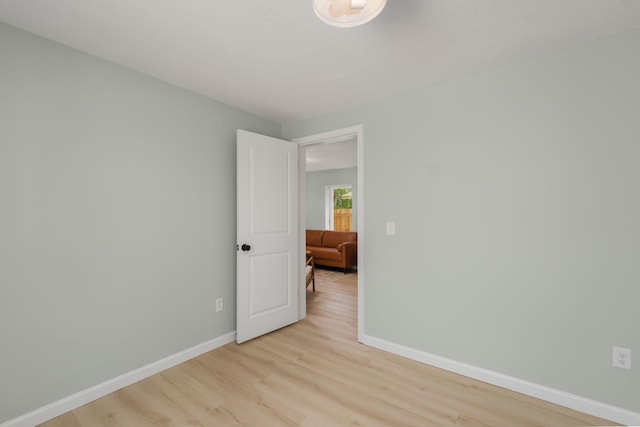 spare room with baseboards and light wood finished floors