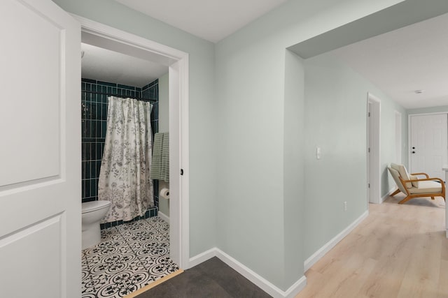 hall featuring baseboards and wood finished floors