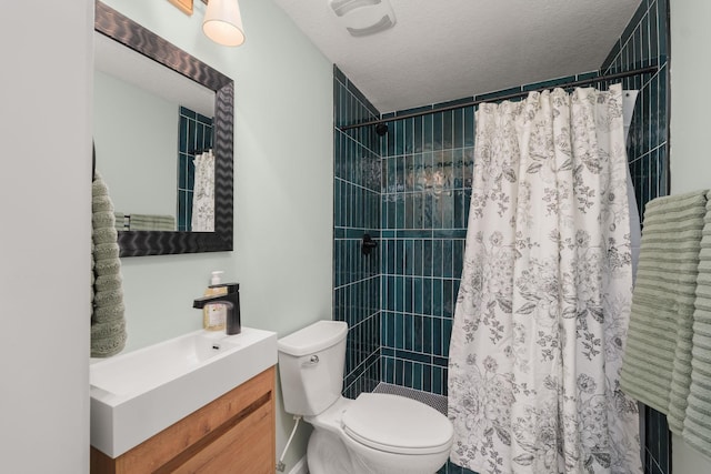 bathroom featuring toilet, a tile shower, vanity, and a textured ceiling