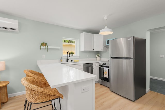 kitchen featuring appliances with stainless steel finishes, a wall mounted air conditioner, light countertops, a peninsula, and a breakfast bar