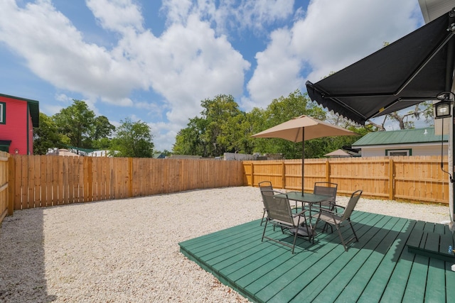 fenced backyard with outdoor dining area and a wooden deck
