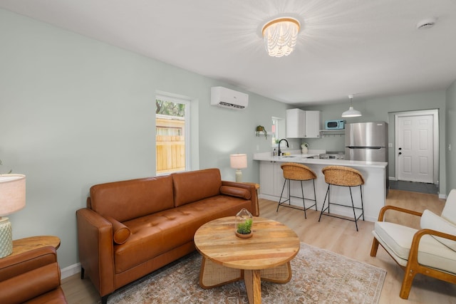 living room featuring a wall unit AC, light wood-style flooring, and baseboards