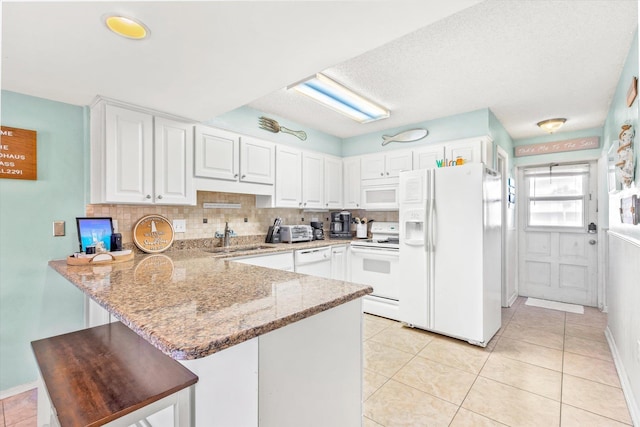 kitchen featuring kitchen peninsula, tasteful backsplash, white appliances, sink, and white cabinets