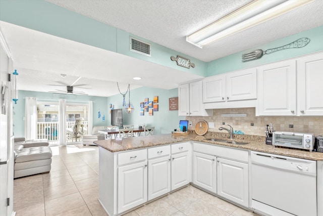 kitchen with kitchen peninsula, backsplash, white dishwasher, sink, and white cabinetry