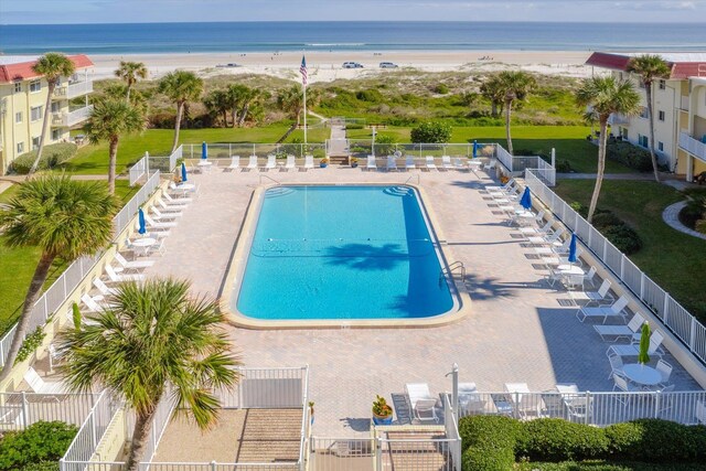 view of pool with a patio area, a water view, and a view of the beach