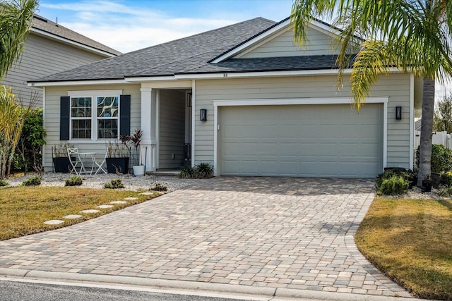 view of front of property with a shingled roof, decorative driveway, and an attached garage