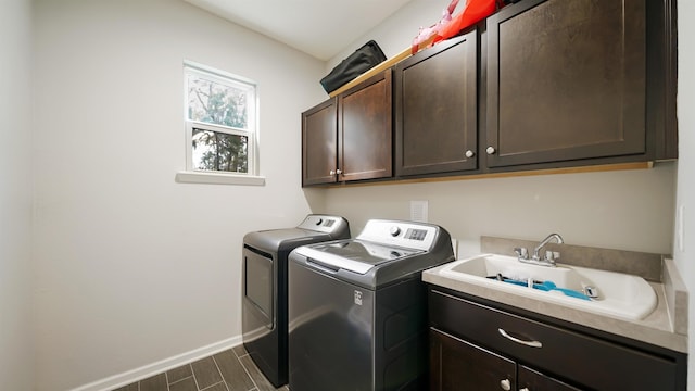 laundry room featuring washer and clothes dryer, cabinet space, wood tiled floor, a sink, and baseboards