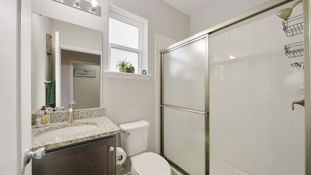 full bath featuring tiled shower, vanity, and toilet