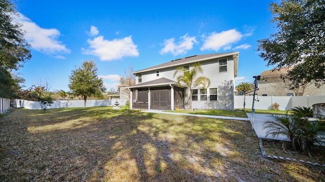 back of house with a sunroom, a fenced backyard, a lawn, and stucco siding