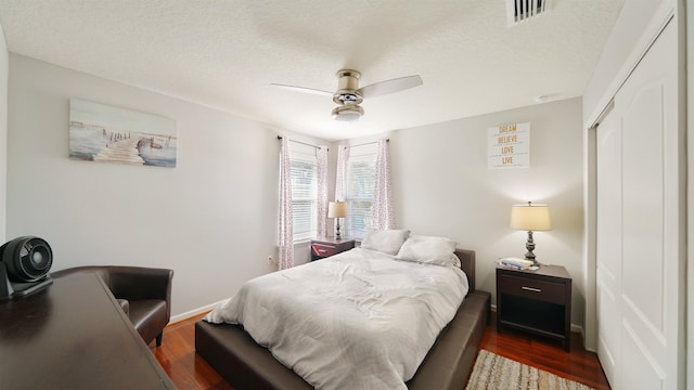 bedroom with a closet, visible vents, a ceiling fan, wood finished floors, and baseboards