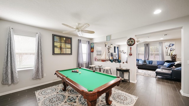 game room featuring a ceiling fan, a healthy amount of sunlight, and dark wood finished floors