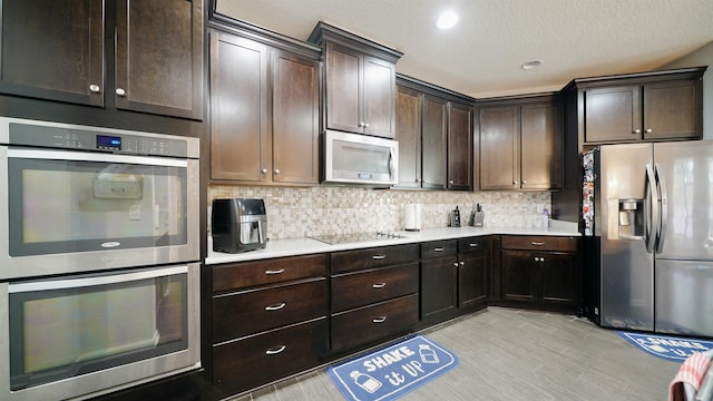 kitchen with dark brown cabinetry, appliances with stainless steel finishes, light countertops, and backsplash