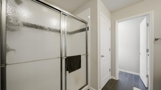 full bathroom with a stall shower, baseboards, and wood finished floors