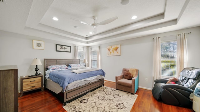 bedroom featuring ceiling fan, recessed lighting, dark wood-style flooring, baseboards, and a raised ceiling