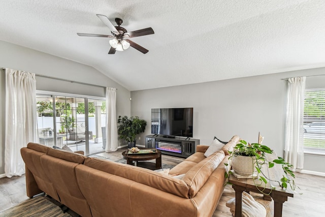 living room with vaulted ceiling, ceiling fan, wood finished floors, a textured ceiling, and baseboards