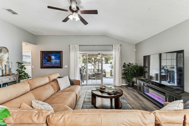 living area with wood finished floors, lofted ceiling, a ceiling fan, and a textured ceiling