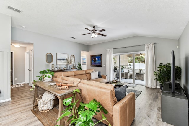 living room featuring wood finished floors, ceiling fan, vaulted ceiling, baseboards, and a textured ceiling