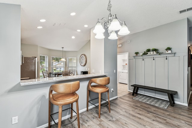 kitchen featuring washer / clothes dryer, freestanding refrigerator, wood finished floors, a chandelier, and recessed lighting