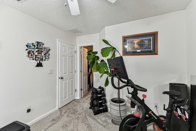 workout room featuring light carpet, baseboards, and a textured ceiling