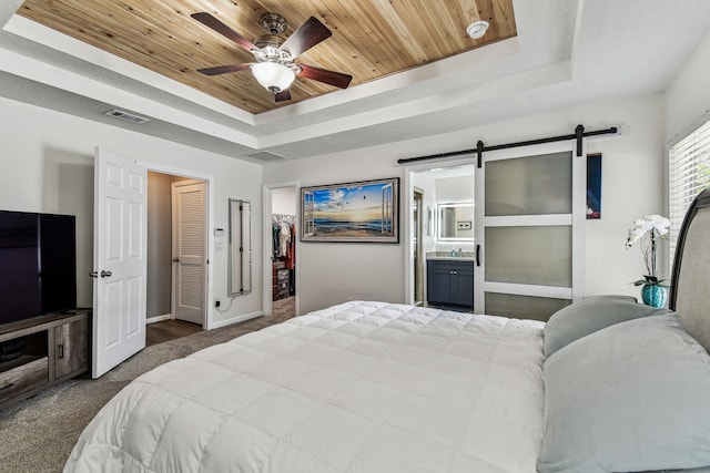 bedroom with a raised ceiling, a barn door, carpet, wood ceiling, and baseboards