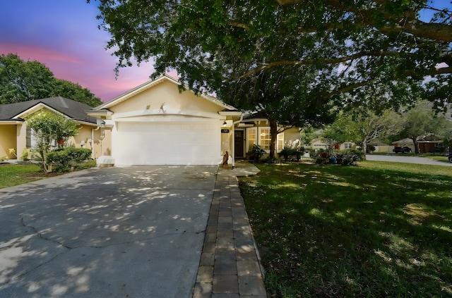 view of front of property with an attached garage, concrete driveway, stucco siding, and a lawn