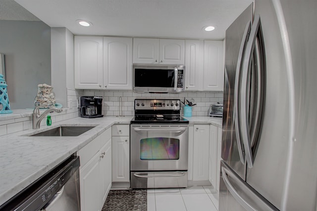 kitchen with white cabinets, sink, light tile patterned floors, light stone counters, and stainless steel appliances