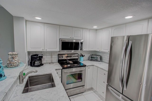 kitchen featuring white cabinets, light stone counters, sink, and stainless steel appliances