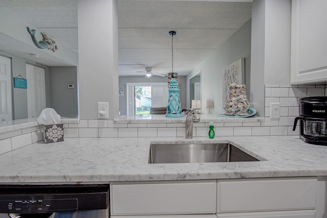 kitchen featuring backsplash, light stone counters, sink, dishwasher, and white cabinetry