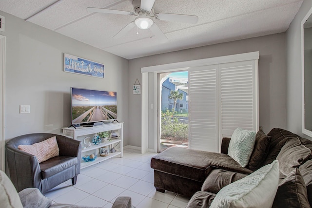 living room featuring ceiling fan, light tile patterned floors, and a textured ceiling