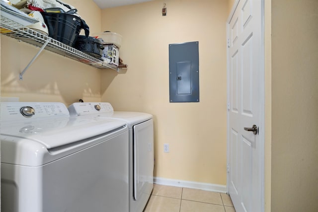 clothes washing area with electric panel, light tile patterned flooring, washing machine and clothes dryer, laundry area, and baseboards
